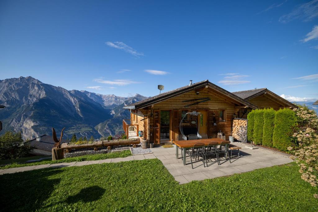 eine Blockhütte mit einem Tisch, Stühlen und Bergen in der Unterkunft Chalet Chanterelle - Cosy et montagnard in Plan Fey