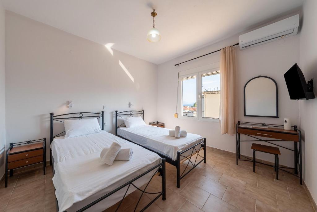 2 bedden in een kamer met een spiegel en een bureau bij Gavriil Apartment G2 in Corfu