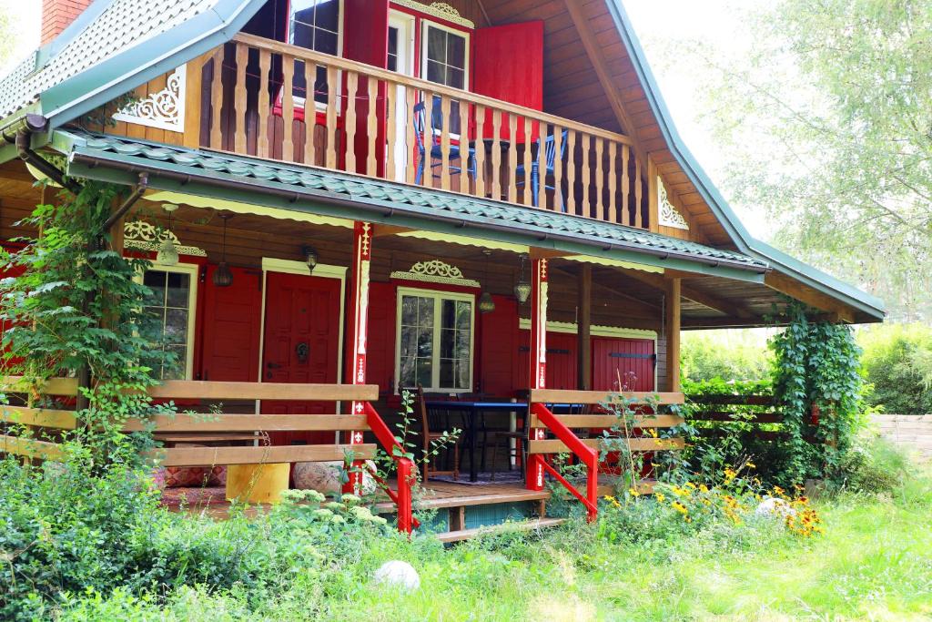 a red house with a porch and a balcony at Chata Wiedźmy - Sanktuarium Laparica w Puszczy Białej 