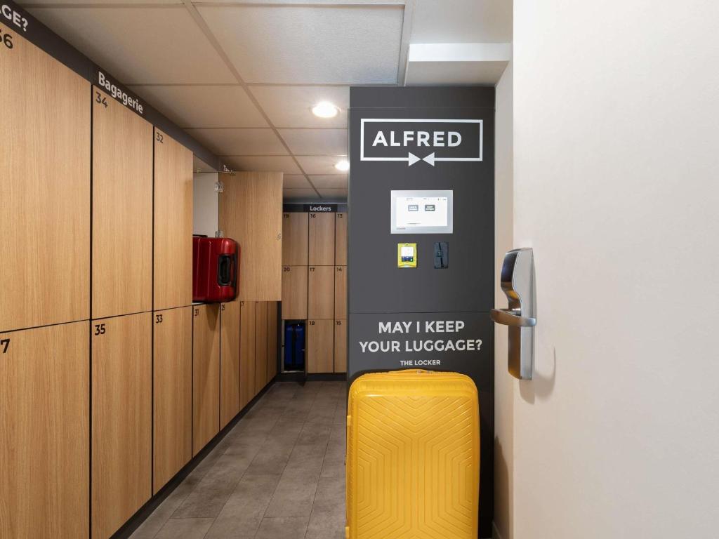 Un pasillo con una maleta amarilla en un vestuario. en ibis Paris Porte de Montreuil, en París