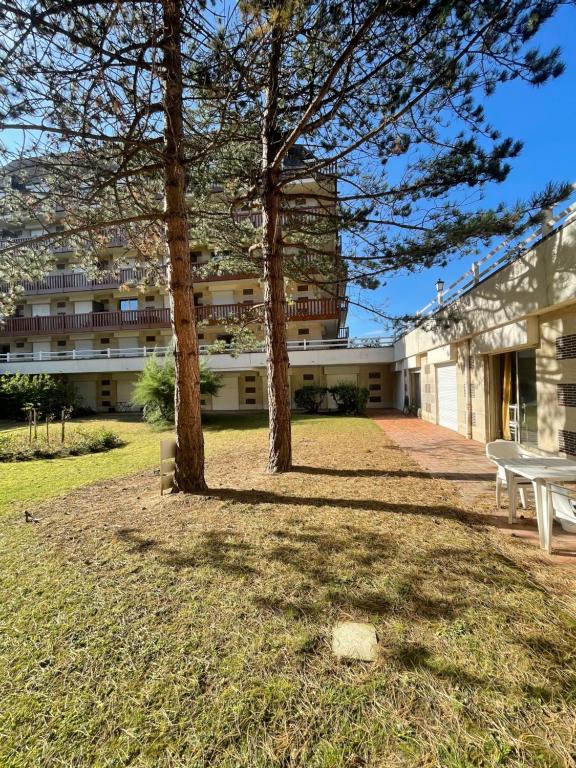 a park with two trees in front of a building at Le Loft Bleu Deauville - les Petites Planches in Deauville
