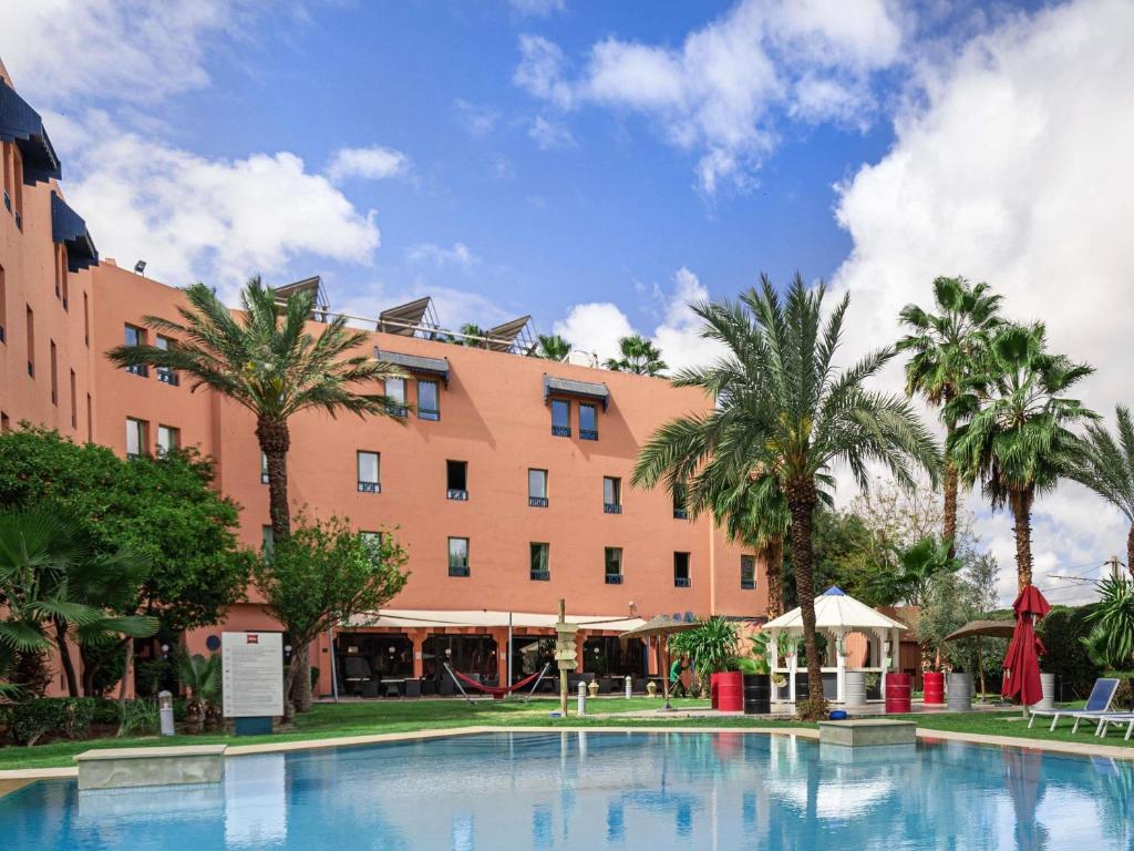 a hotel with a swimming pool in front of a building at Ibis Marrakech Centre Gare in Marrakech