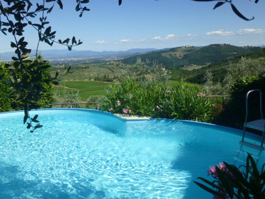 una piscina azul con vistas a las montañas en La Solaria, en Carmignano
