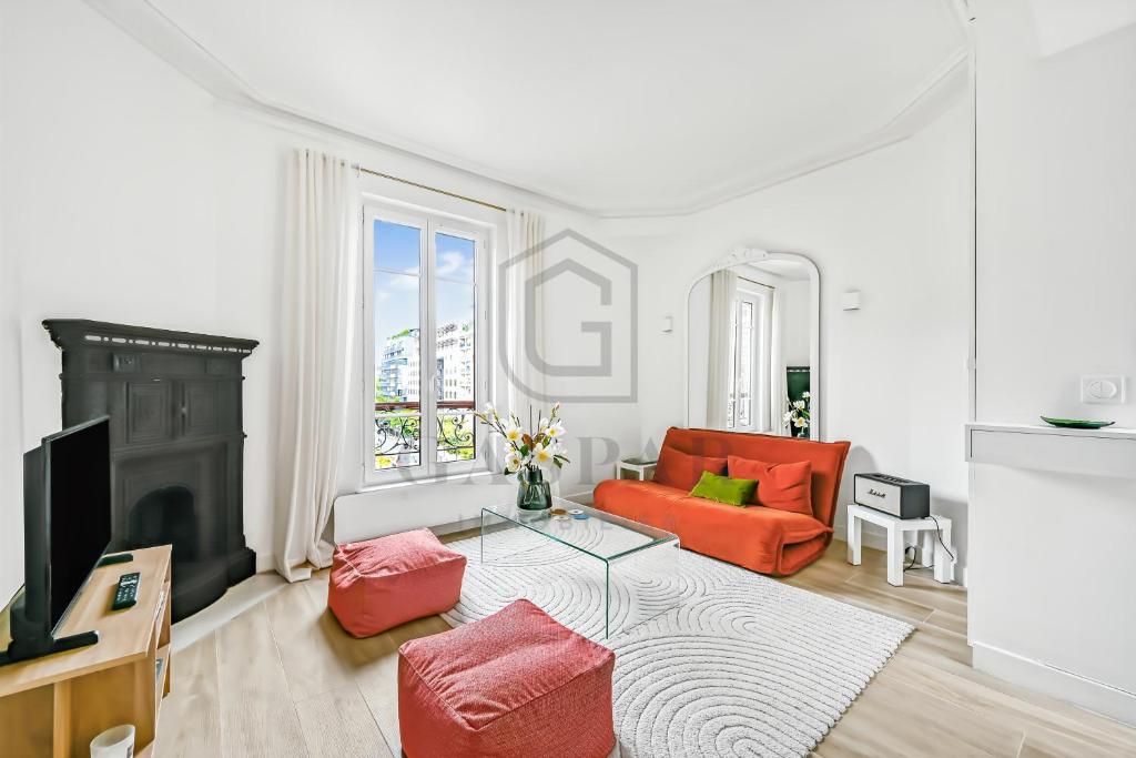a living room with an orange couch and a tv at Gaspar- Passages- Comfort & proximity to Paris in Boulogne-Billancourt