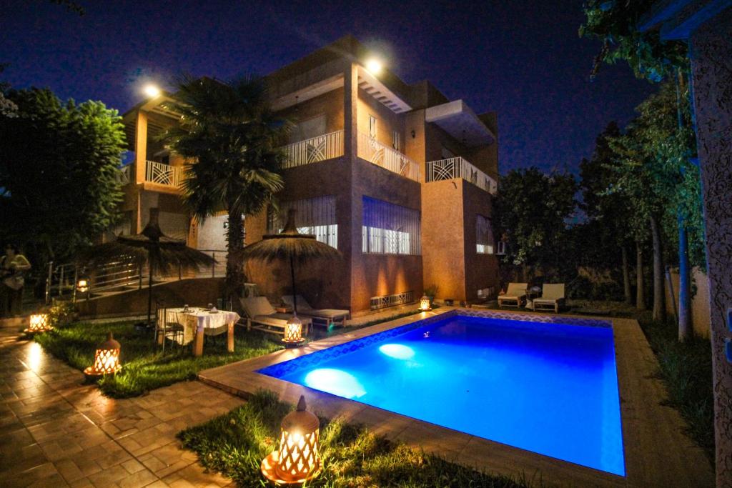a large house with a large swimming pool at night at Redmoon Villa & Riad in Marrakech