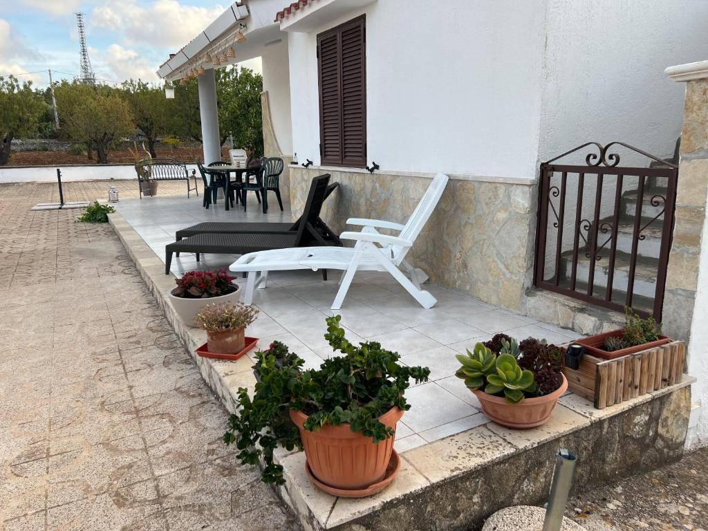 a patio with potted plants and a white chair at Villa Mimì in Ostuni