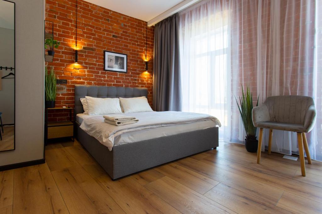 a bedroom with a bed and a brick wall at Сучасна квартира в центрі на Харківській набережній 3-2 in Kharkiv