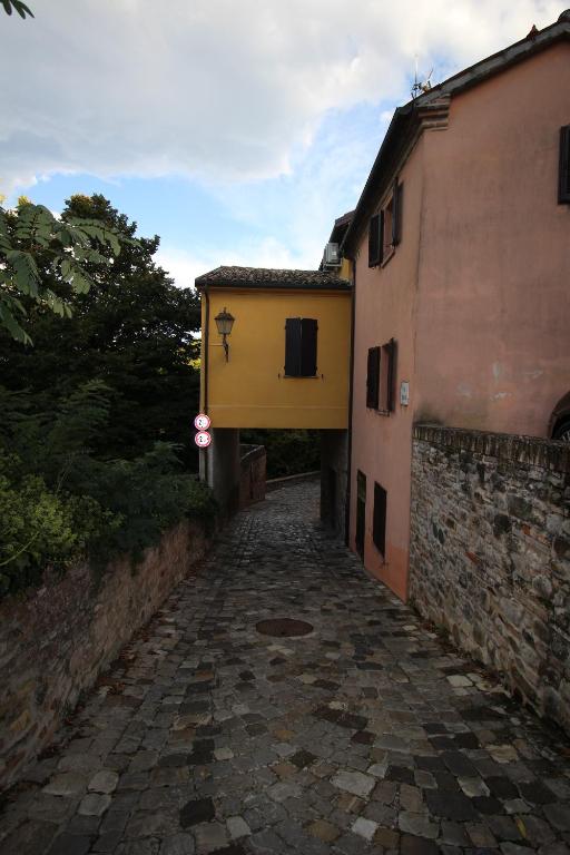 eine Gasse zwischen zwei Gebäuden mit einem gelben Gebäude in der Unterkunft La Casetta Sulle Mura in Santarcangelo di Romagna