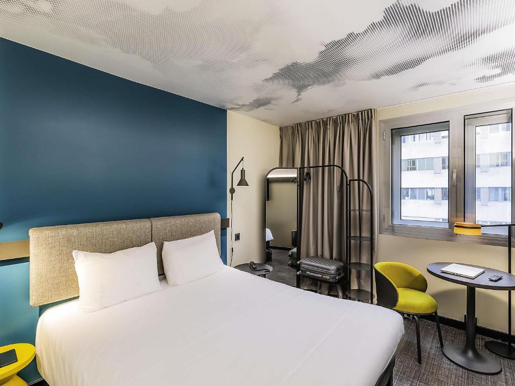 a bedroom with a white bed and a blue wall at Hotel ibis Lisboa Saldanha in Lisbon