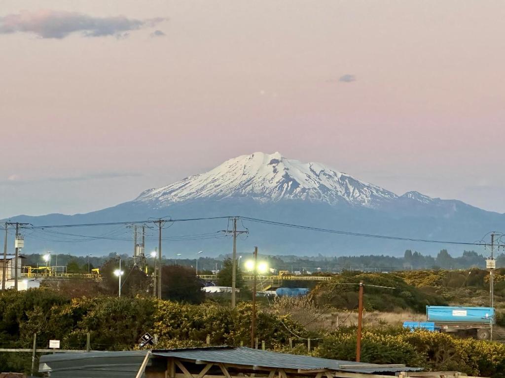 a snow covered mountain in the distance with a city at Latitud Guesthouse in Puerto Montt
