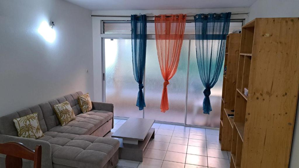 a living room with a couch and a large window at Appartement confortable à Le Lamentin, 70 m², jardin in Chambort