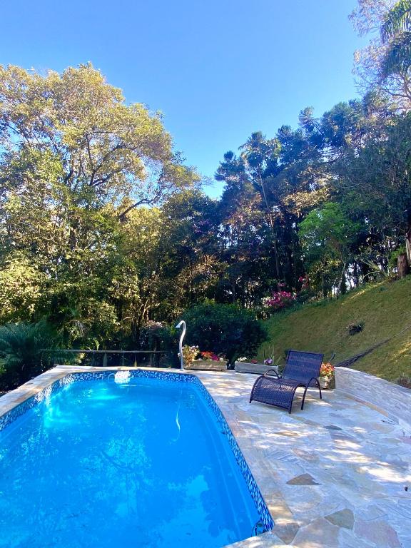 a swimming pool with a bench and a bird in a yard at Chácara Recanto do Berzelai in Bueno Brandão