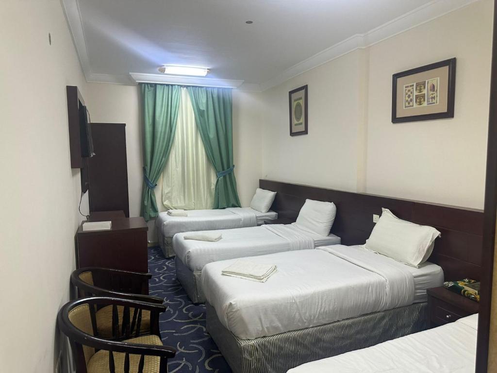 a hotel room with three beds and a window at فندق درة الراشدين in An Naqāʼ