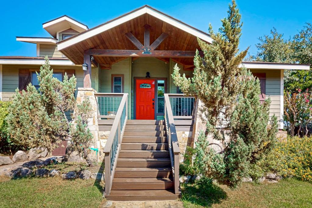 Casa con puerta roja y escalera de madera en Clutter Falls Retreat - Main House, en Gruene