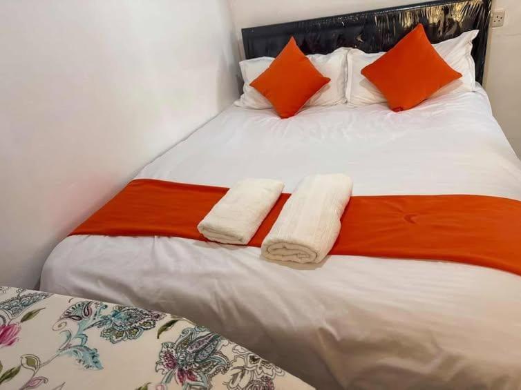 a bed with orange and white sheets and orange pillows at Serene suites in Nyahururu