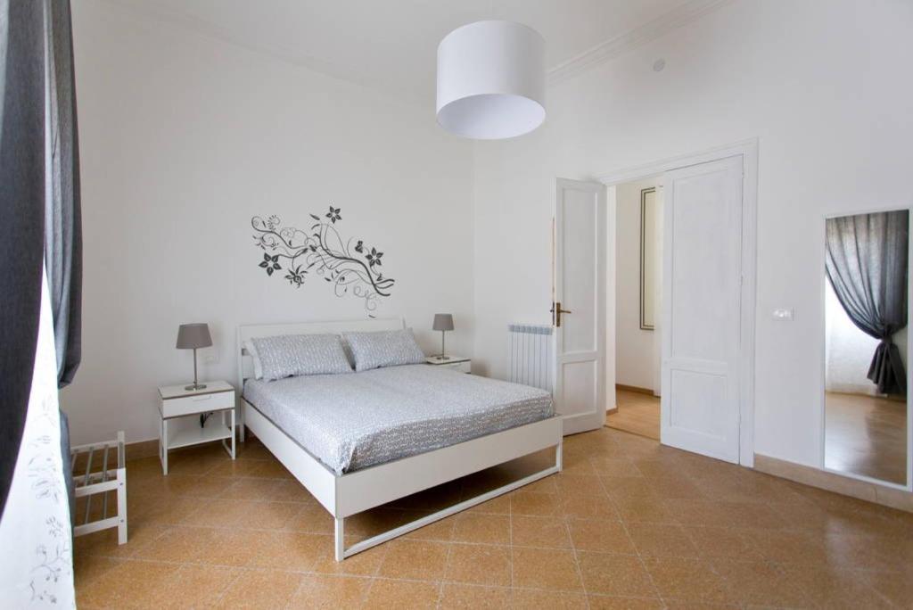 a white bedroom with a bed and a white wall at Caselita in Palermo