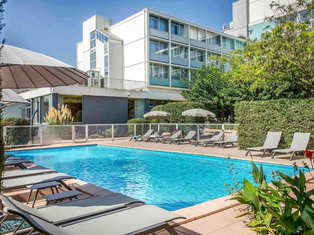 ein Swimmingpool mit Liegestühlen und ein Gebäude in der Unterkunft Ibis Cavaillon Portes du Luberon in Cavaillon