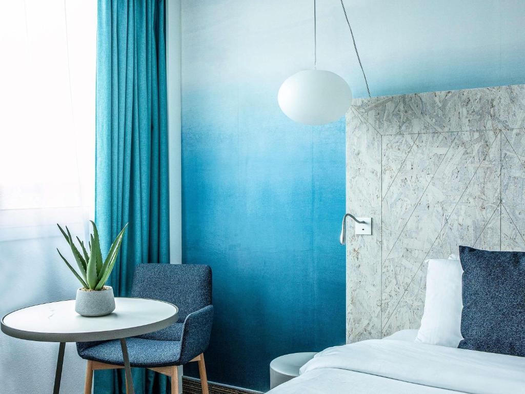 a bedroom with a bed and a table and a table and chairs at Mercure Vannes Le Port in Vannes