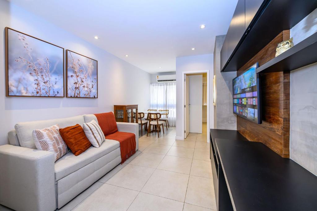 a living room with a couch and a flat screen tv at Live a dream in the heart of LEBLON in Rio de Janeiro