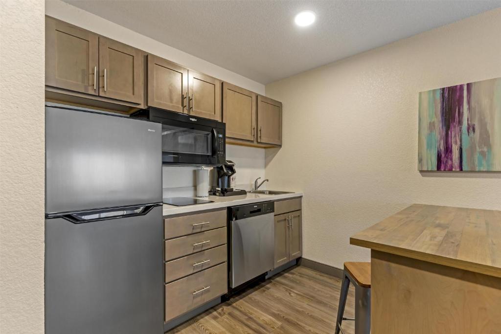 eine Küche mit Edelstahlkühlschrank und Holzschränken in der Unterkunft Executive Residency by Best Western Waterloo & Cedar Falls in Waterloo