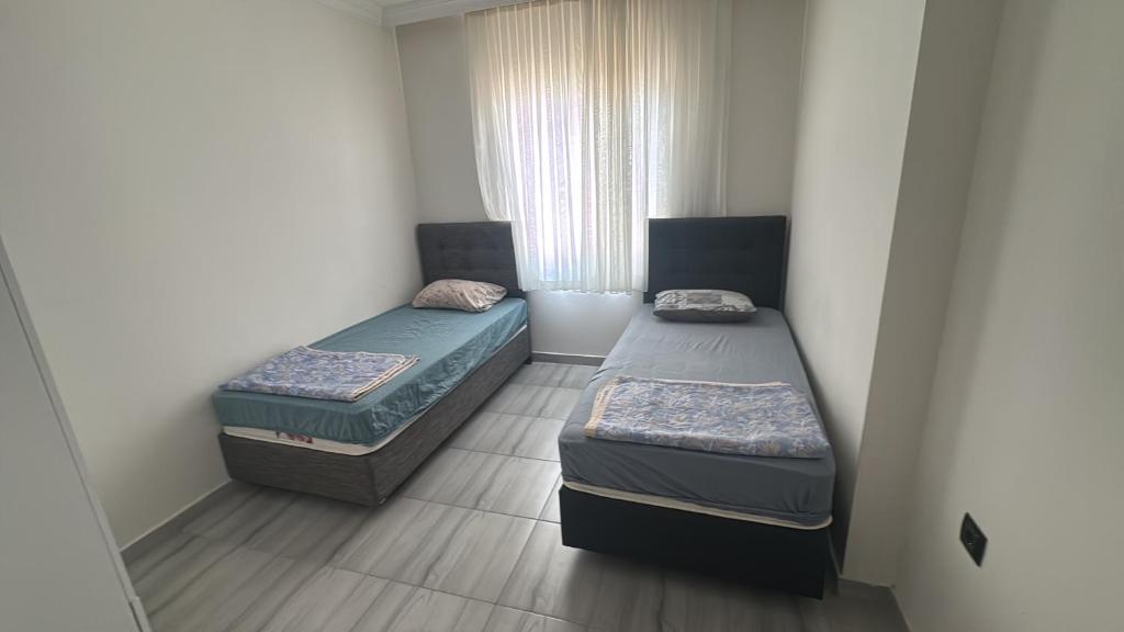 twee bedden in een kleine kamer met een raam bij Köşk Rezidans 