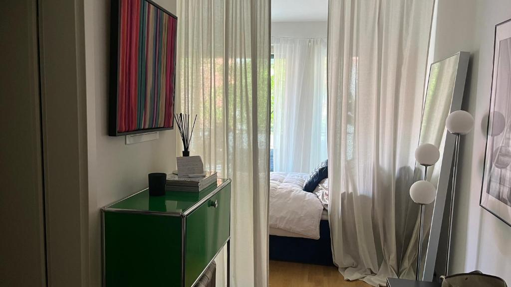 a bedroom with a bed and a green cabinet with a window at Modern & Cozy Apartment Münchner Freiheit with Balcony in Munich