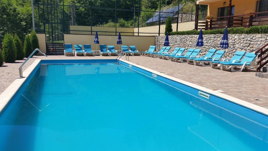 Una piscina con tumbonas y un resort. en Pension Curmatura Stezii, en Răşinari