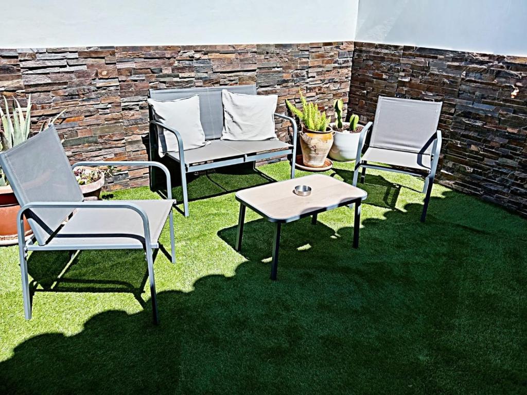 three chairs and a table on a lawn at Apartamentos María Gaviota 2 in Prado del Rey