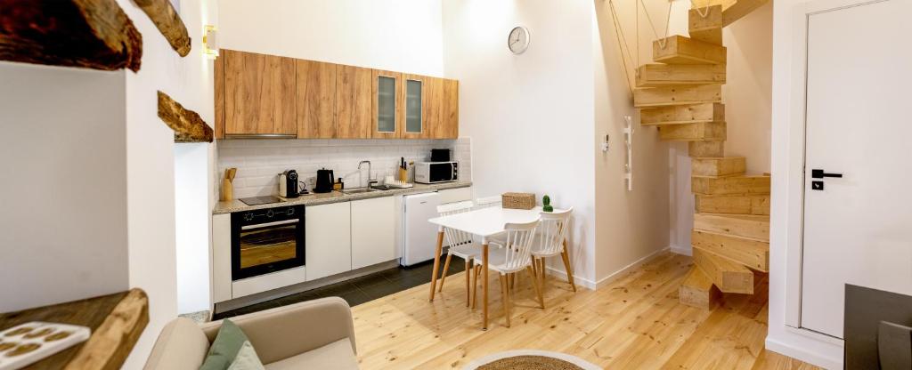 una cucina con mobili bianchi, tavolo e sedie di Casas do Freixial - Casa das Flores a Fundão