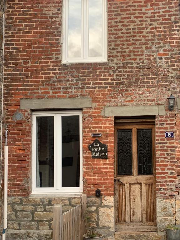a brick building with a door and a sign on it at La Petite Maison, Perrou, Normandy, Orne in Perrou