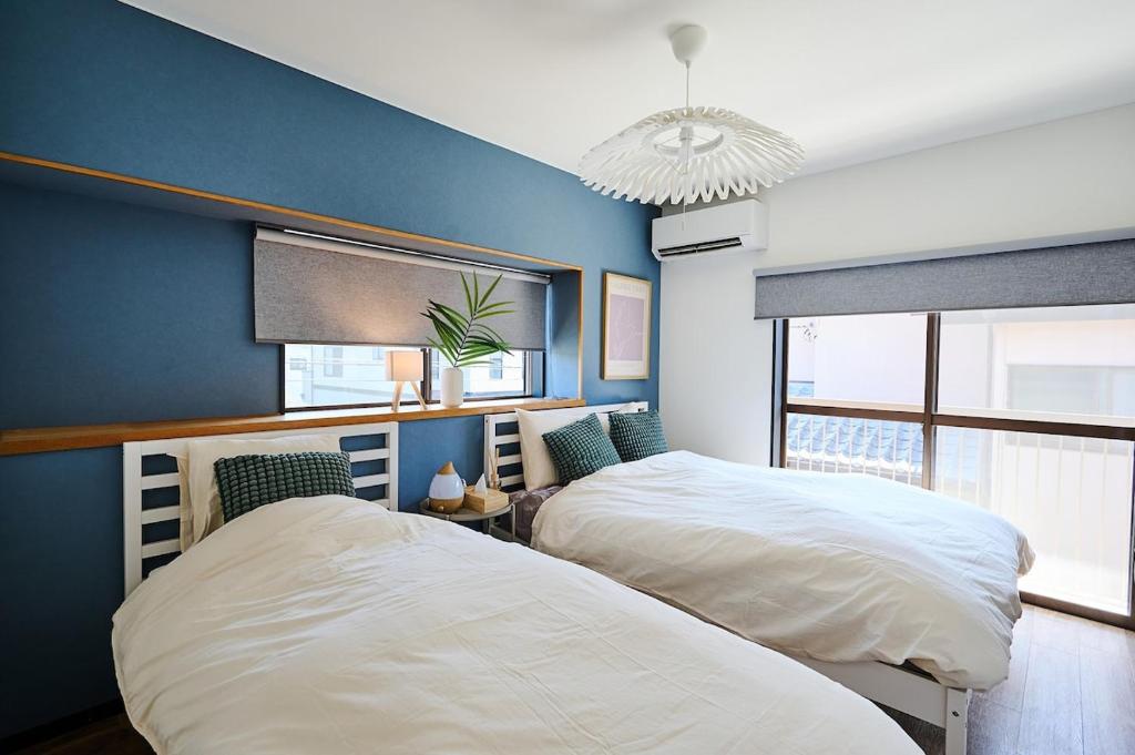 two beds in a bedroom with a blue wall at IZUMI HOUSE - 成田空港から車で22分 - 最大8名 - 駐車場2台完備 - Switch有 - 10月28日以降ペット歓迎 in Yachimata