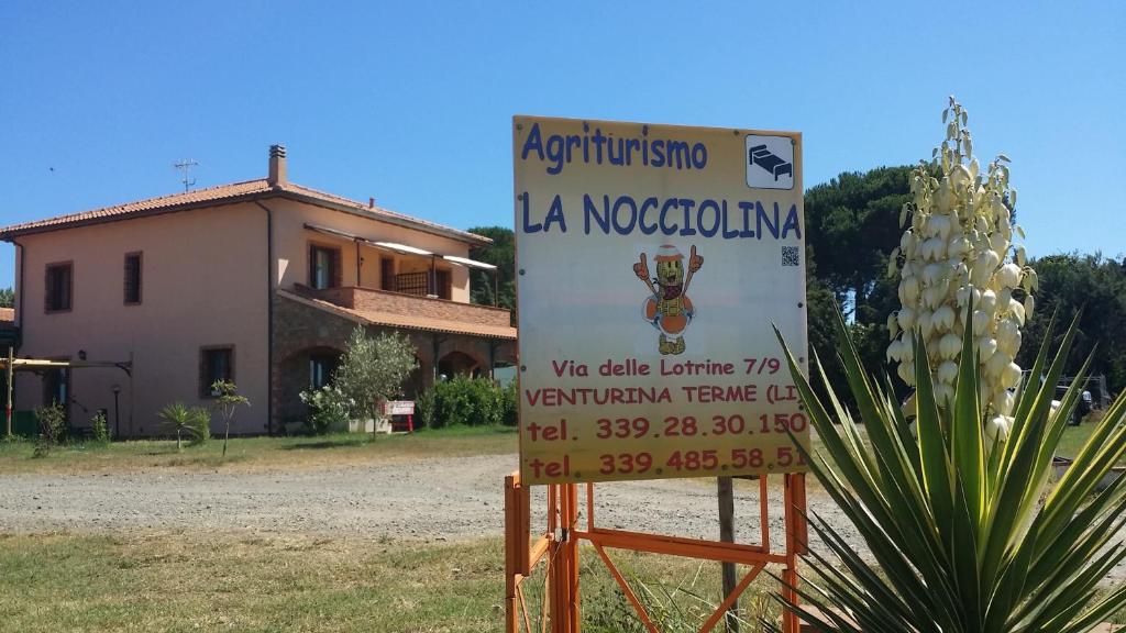 um sinal na frente de uma casa ao lado de uma planta em Agriturismo La Nocciolina em Venturina Terme