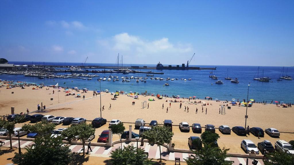 a beach with a lot of people and boats in the water at Sadurni Apartaments in Palamós