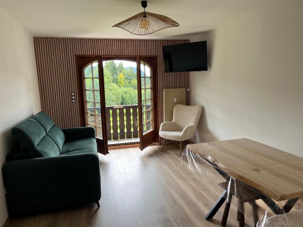 a living room with a couch and a table and a window at Studio cosy proche du centre in Les Gets