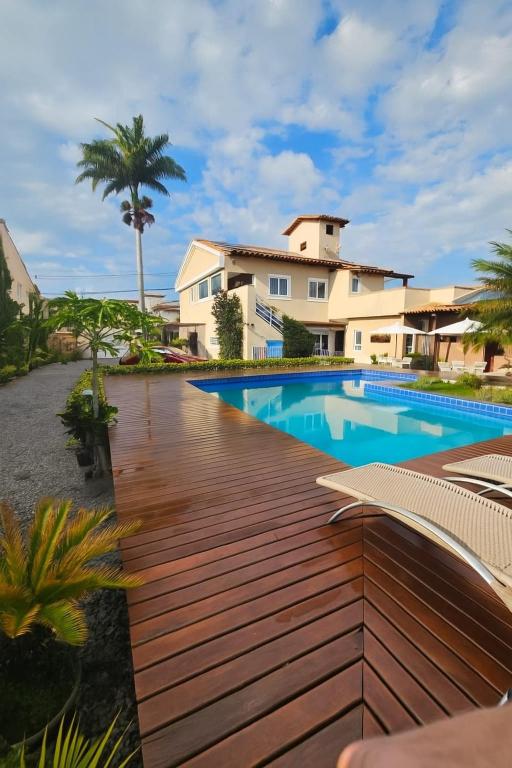 a wooden deck with a swimming pool in front of a house at Pousada do Frei in Búzios