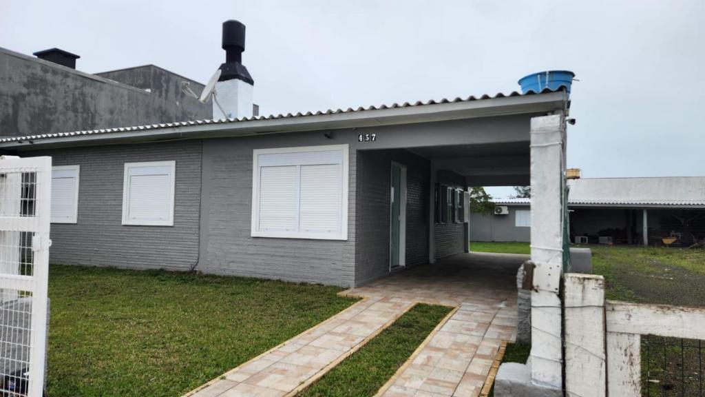 una casa gris con puertas blancas y entrada en Casa de Férias, en Capão da Canoa