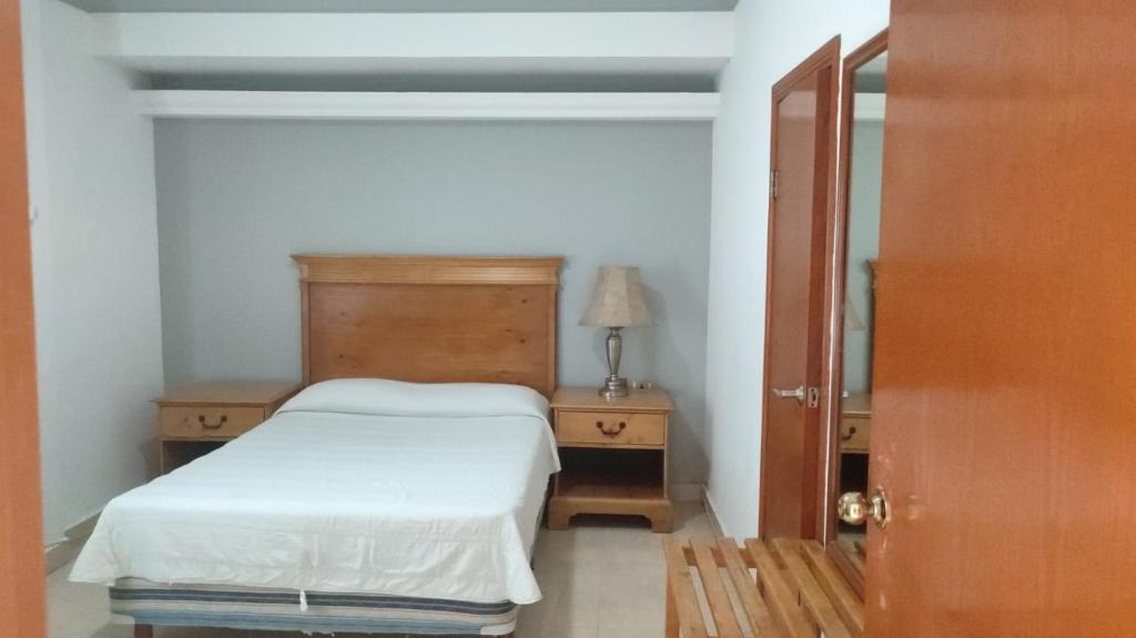 Un dormitorio pequeño con una cama y un espejo. en Hotel los coloniales de reynosa, en Reynosa