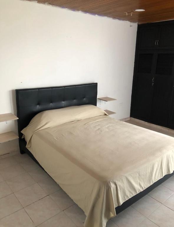 a bed with a black headboard in a bedroom at Habitacion con aire y baño privado in Valledupar
