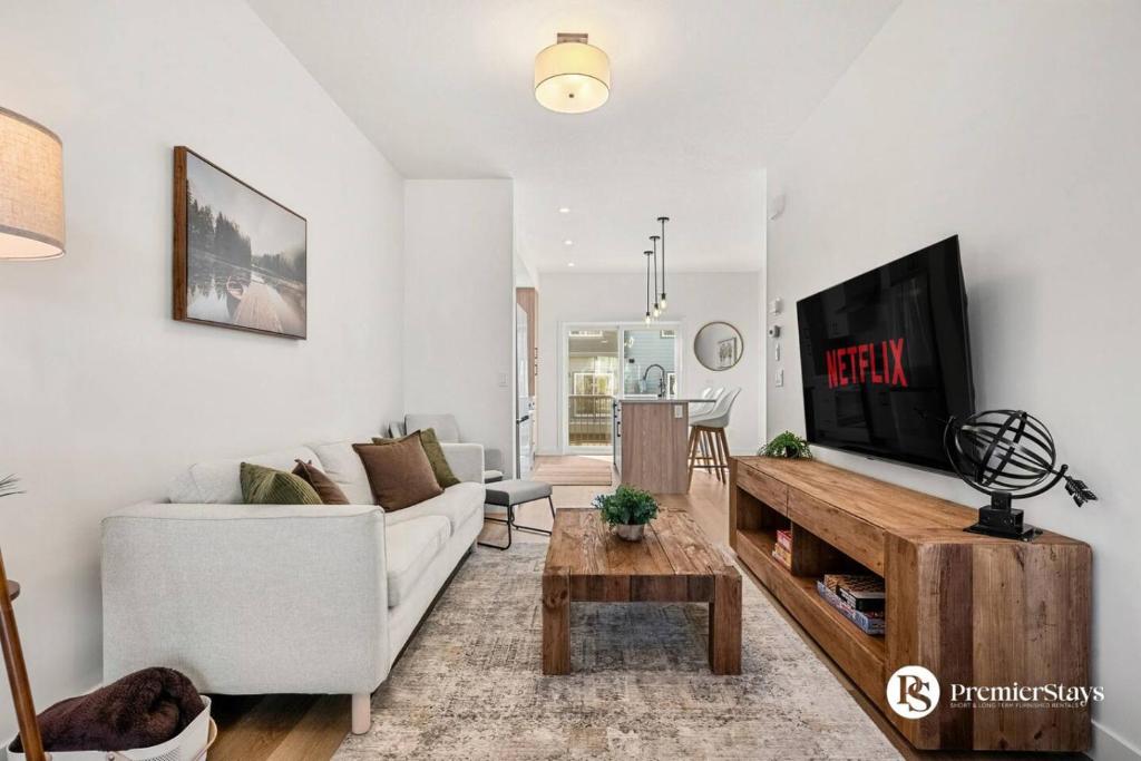 a living room with a white couch and a tv at Modern Luxury Townhome near Aspen Landing and Winsport in Calgary