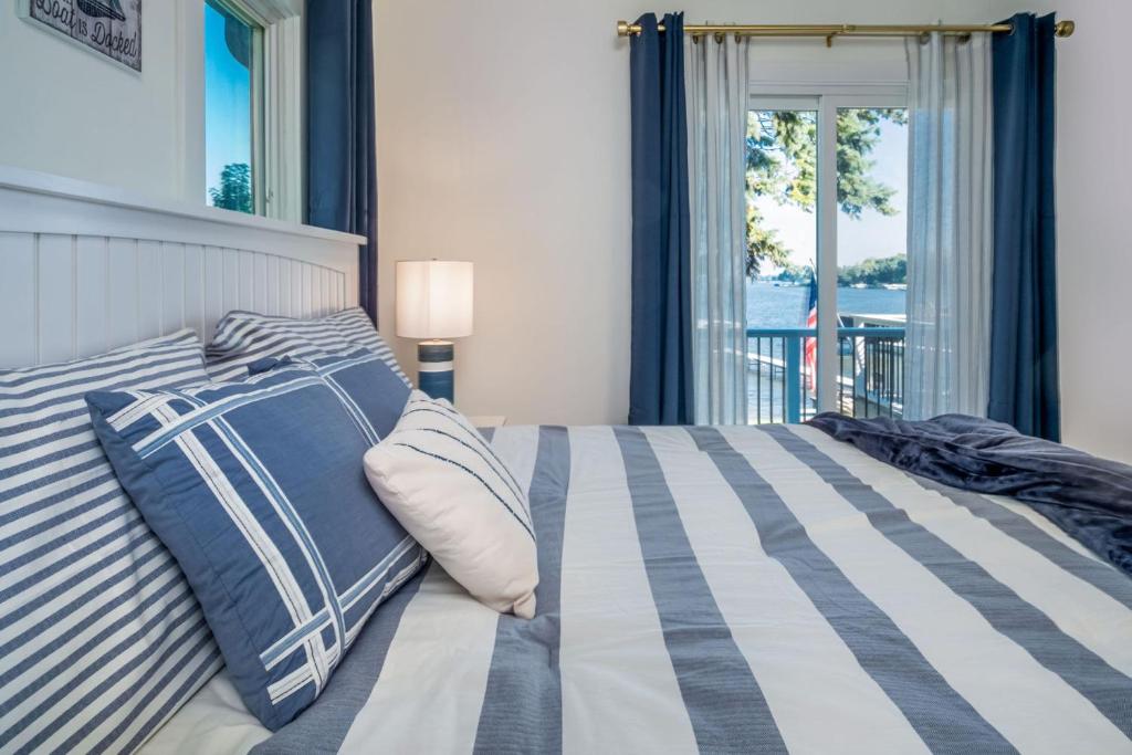 a bedroom with a bed with striped pillows and a window at The Blue Sapphire 3BR 3BA Luxury Lakefront Home on Mineola Bay Stunning Views on Chain O Lakes in Fox Lake