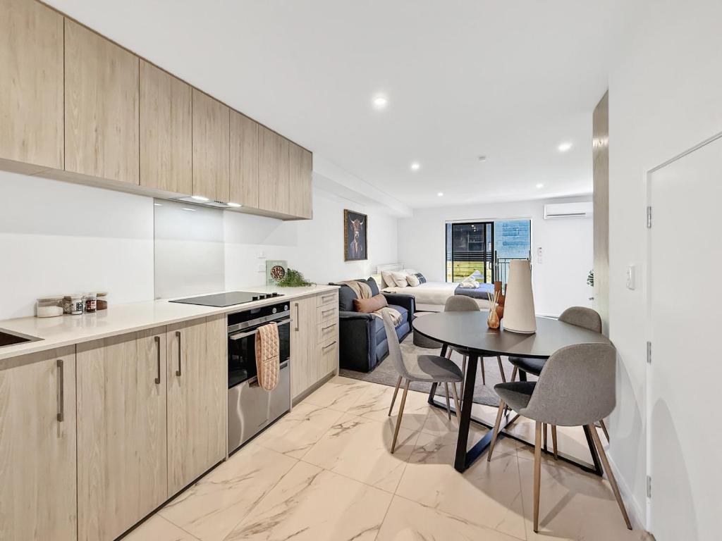 a kitchen with a table and a living room at Cozy Studio with Private Yard in Christchurch CBD in Linwood
