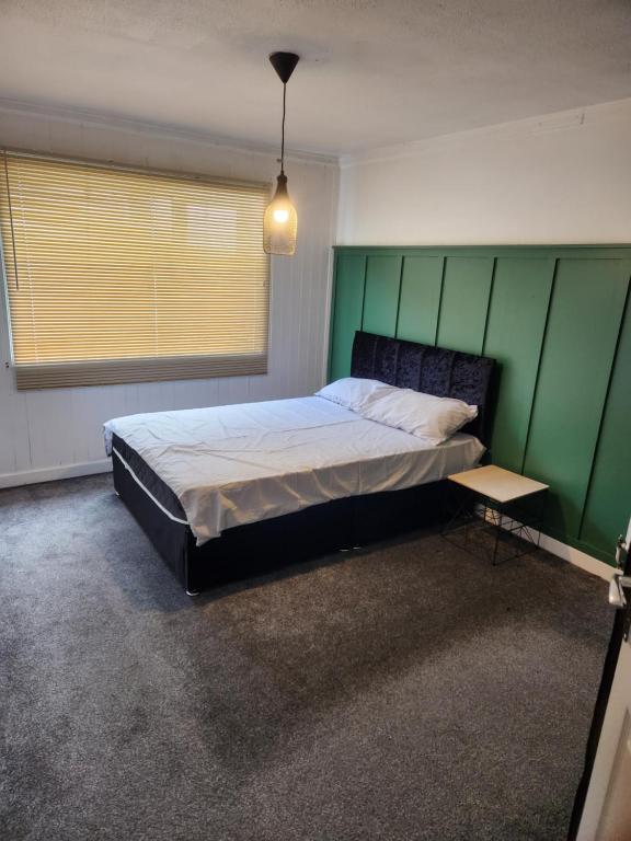 a bedroom with a bed and a green wall at Okwute,s House in Skelmersdale