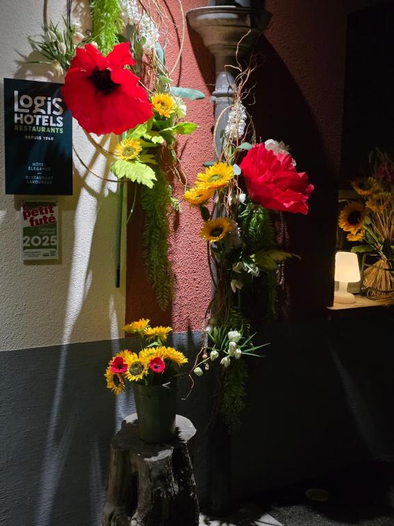 a bunch of flowers in a vase on a tree stump at Relais Vosgien - Hôtel Restaurant "la Table de Sophia" in Saint-Pierremont