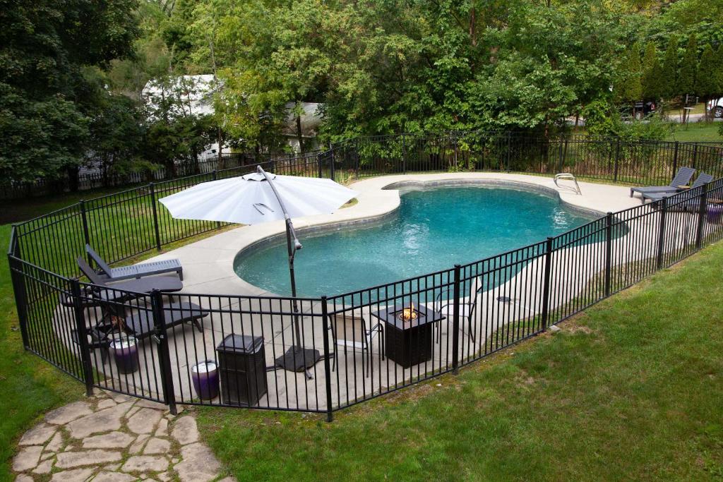 a fence around a pool with an umbrella and chairs at Lakeview on Main Pool Fire Pit and Walkable in Geneva