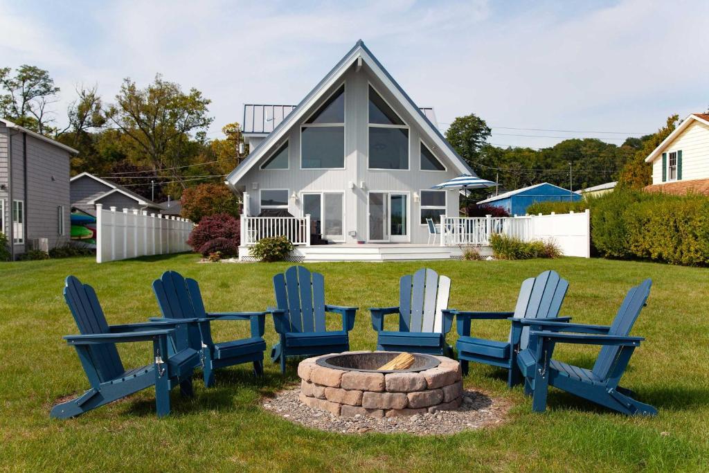 - un groupe de chaises autour d'un foyer extérieur devant une maison dans l'établissement Katies Cottage Lakefront Stay with Hot Tub and Kayaks, à Teall Beach