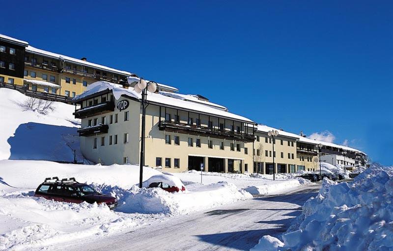 a snow covered building with a car parked in the snow at Studio on the ski slopes in Passo del Tonale