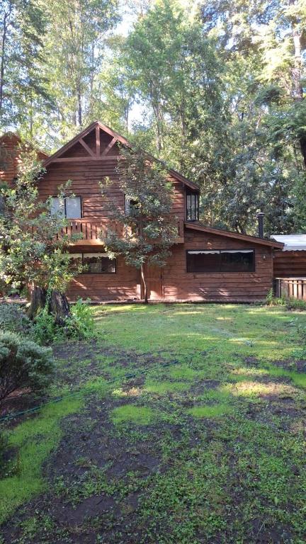 a wooden house with a yard in front of it at Nidos del Chucao in Pucón