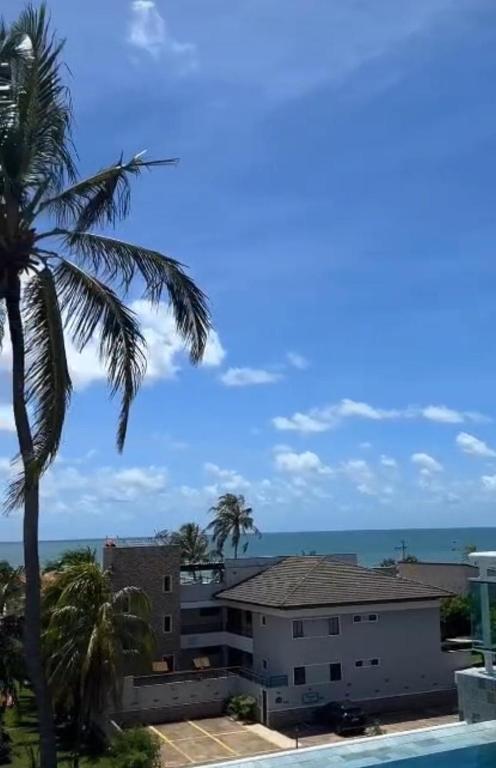 a palm tree and a building with the ocean in the background at Paraíso em Flecheiras in Trairi