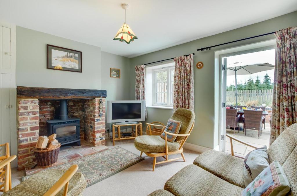 a living room with a fireplace and a tv at Keepers Cottage in Sall