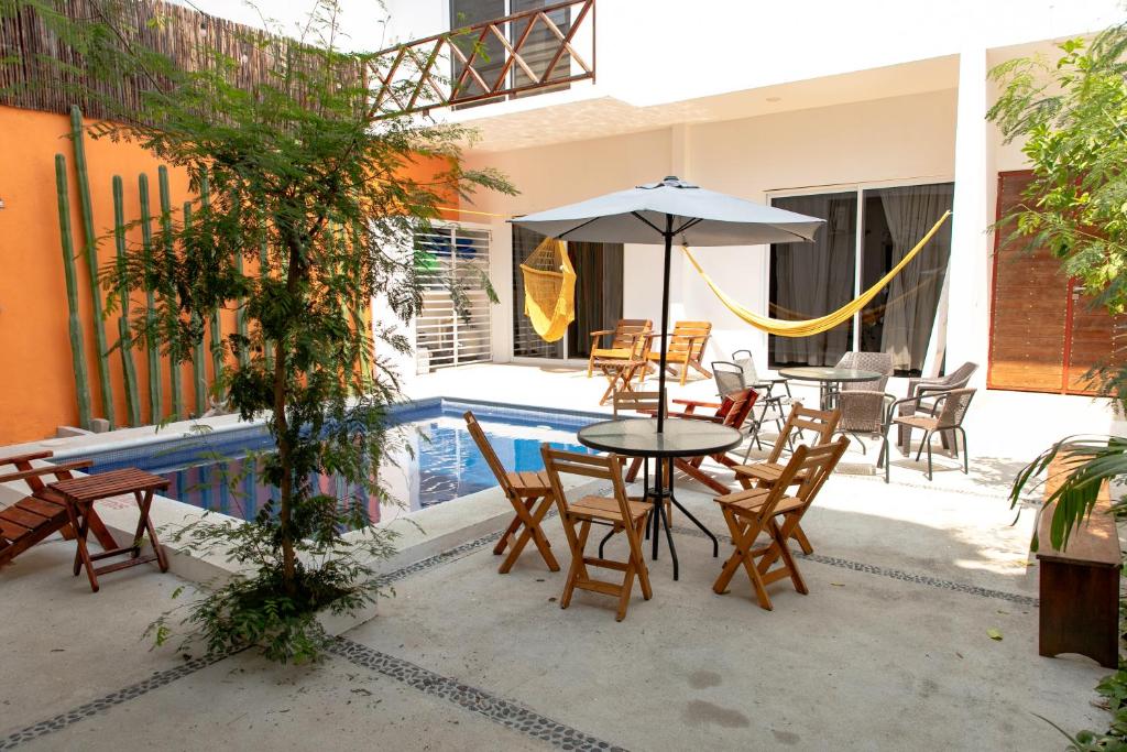 Una mesa y sillas con una sombrilla junto a una piscina. en Spacious 6 AC Bedrooms Ocean View House up to 16 Guests 7 min walking from Puerto Escondido Best Beaches Playa Coral Bacocho y Carrizalillo, en Puerto Escondido